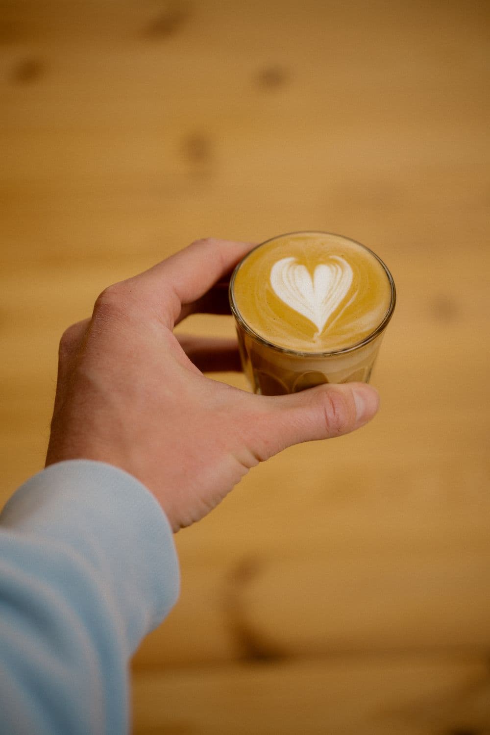 Cortado with heart latte art held in hand