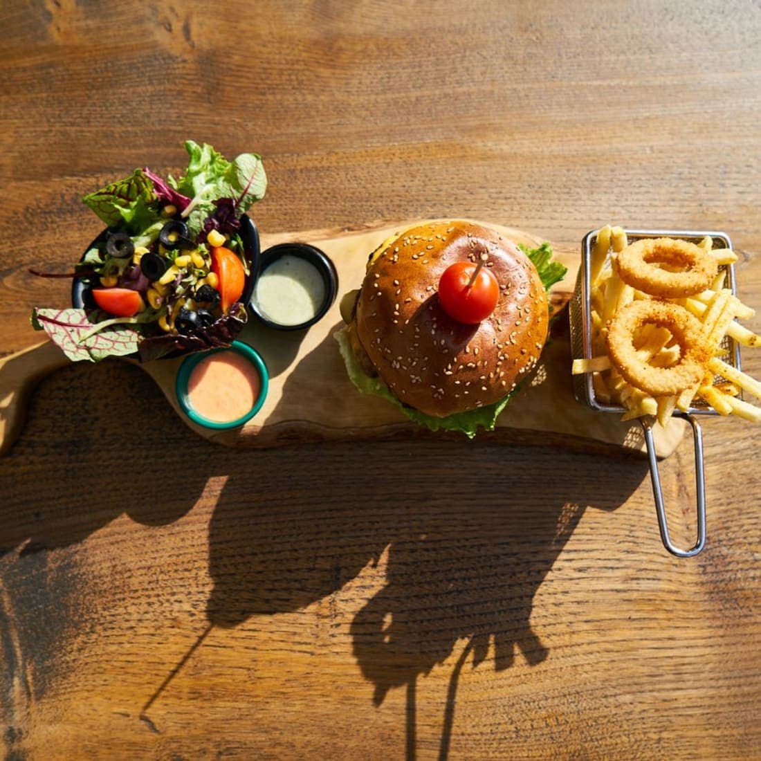 Loaded burger with fries and onion rings on a board